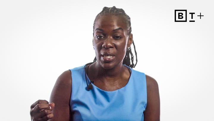A woman in a blue sleeveless top speaks while gesturing with her hand. She wears a microphone headset. The BT+ logo appears in the top right corner.