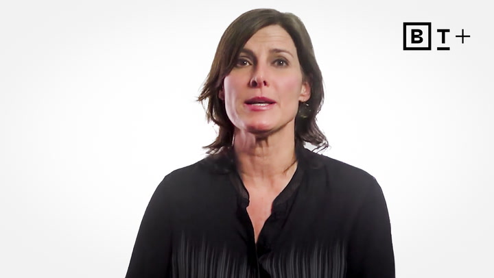 A woman with short brown hair wearing a black blouse speaks in front of a white background with a "BT+" logo in the top right corner.