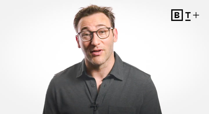 A man with short hair and glasses wearing a dark shirt stands against a plain white background with a "B T +" logo in the top right corner.