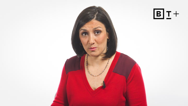 A woman with straight dark hair wearing a red top looks at the camera against a plain white background with a "BT+" logo in the corner.