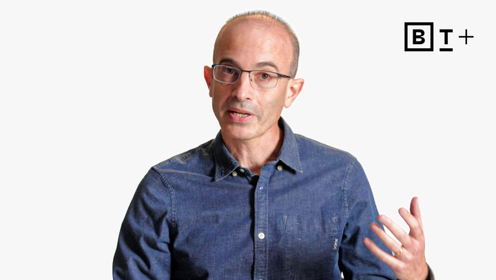 A man in glasses and a blue button-up shirt speaks with one hand raised; a "B T +" logo appears in the top right corner.