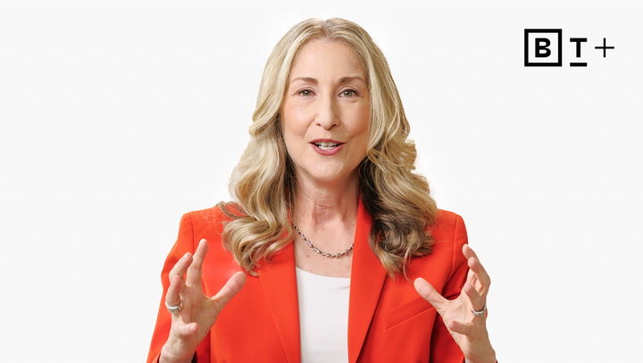A woman with long blonde hair wearing a red blazer gestures with her hands while speaking; a "BT+" logo is in the upper right corner.