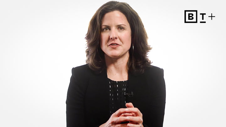 A woman with shoulder-length dark hair wearing a black blazer sits against a white background with a "BT+" logo in the top right corner.