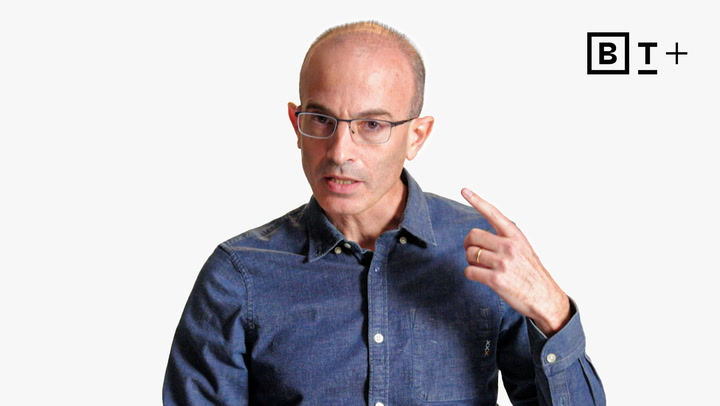 A man wearing glasses and a blue button-up shirt gestures with his right hand, pointing to his head. A stylized "B T+" logo appears in the top right corner on a white background.