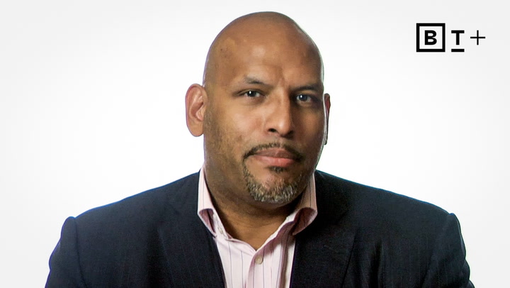 A man in a suit and collared shirt poses in front of a plain white background with the BT+ logo in the top right corner.