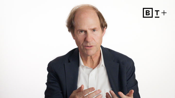 A middle-aged man with thinning hair, wearing a dark blazer and white shirt, speaks against a plain white background with a "BT+" logo in the top right corner.