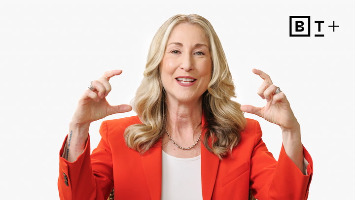 A woman with long blonde hair in an orange blazer gestures with both hands, forming a "C" shape. A black and white "B T+" logo appears in the top right corner.
