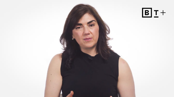 A woman with dark hair in a sleeveless black top speaks in front of a plain white background with a "BT+" logo in the top right corner.