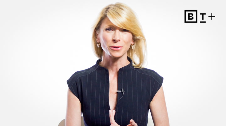 A woman with blonde hair wearing a black, short-sleeved, pinstriped top speaks to the camera against a white background; a "BT+" logo appears in the upper right corner.