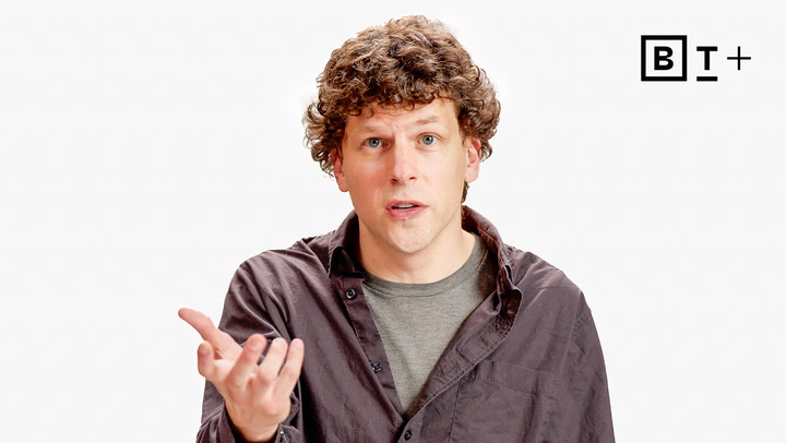 A man with curly hair wearing a dark shirt gestures with his right hand against a plain white background. A "B T +" logo is visible in the top right corner.