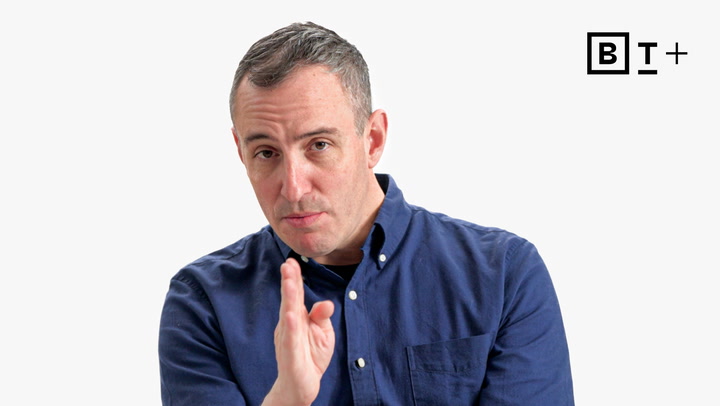 A man in a blue button-up shirt gestures with his hand in front of a white background with a "B T+" logo in the top right corner.