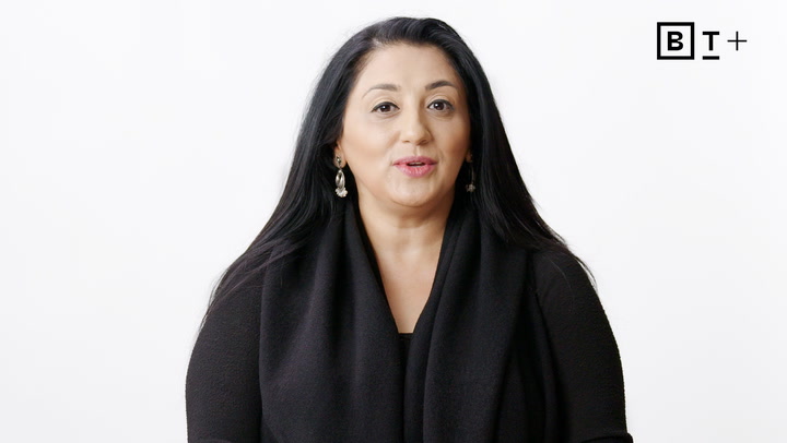 A woman with long black hair wearing a black top and silver earrings is facing the camera against a plain white background. The BT+ logo appears in the top right corner.