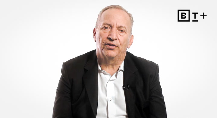 A man in a black suit and white shirt sits against a plain white background with a "B T+" logo in the top right corner.