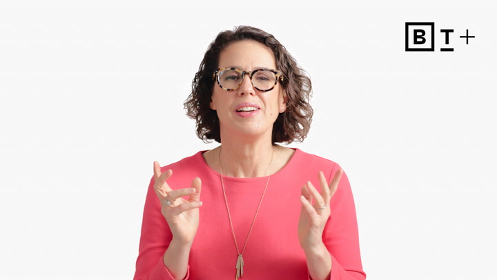A woman with short curly hair and glasses, wearing a pink top and necklace, speaks while gesturing with her hands. A "BT+" logo is visible in the top right corner.