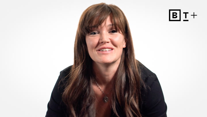 A woman with long brown hair smiles at the camera against a plain white background with the B+ logo in the top right corner.