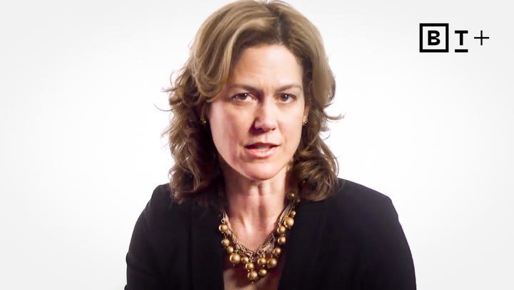 A woman with shoulder-length brown hair wearing a black blazer and a gold beaded necklace speaks in front of a white background with a "BT+" logo in the top right corner.
