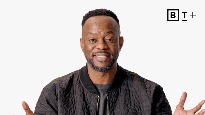 A man wearing a black quilted jacket stands in front of a plain white background with the BT+ logo in the top right corner.