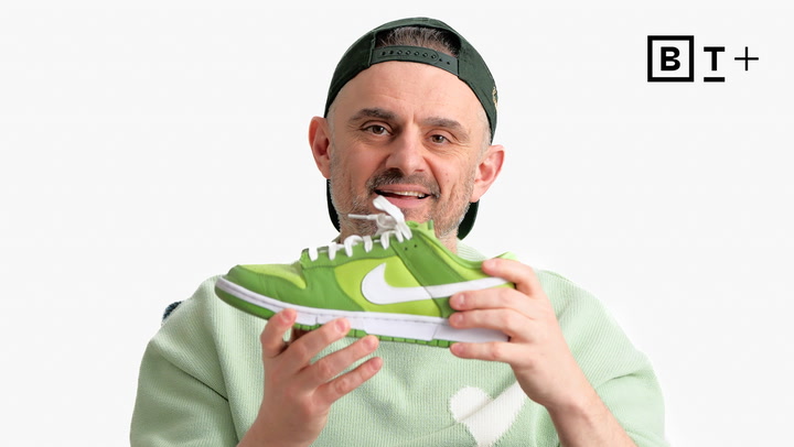 A man wearing a green cap and sweater holds up a green Nike sneaker. The B+ logo is visible in the top right corner.
