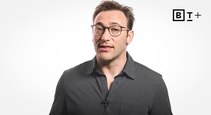 A man wearing glasses and a dark shirt stands in front of a plain white background with a black "B T +" logo in the top right corner.