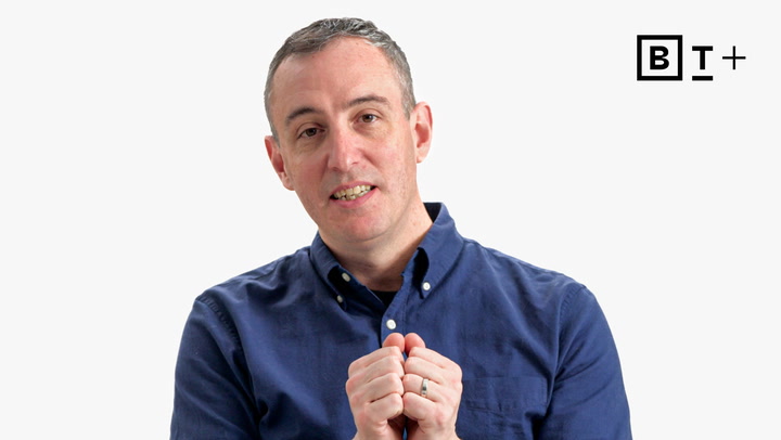 A person in a blue button-up shirt gestures with their hands while looking at the camera. The BT+ logo is visible in the top right corner on a plain background.