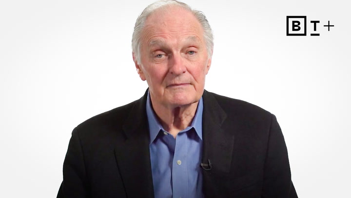 An older man with gray hair wearing a dark blazer and blue shirt sits in front of a plain white background with a "BT+" logo in the top right corner.