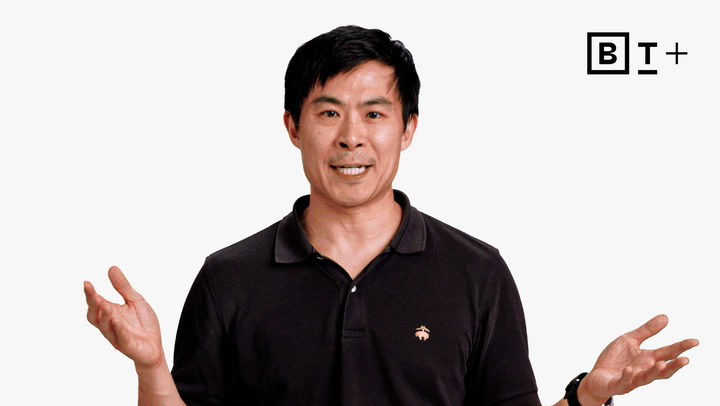 A man in a black polo shirt stands against a plain white background, gesturing with both hands. A logo with the letters "BT+" appears in the top right corner.