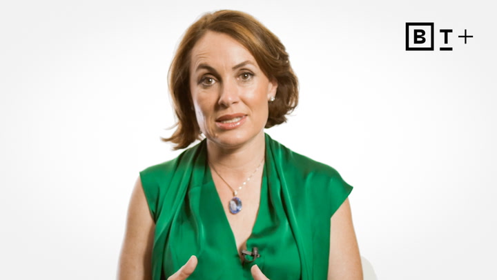 A woman with short brown hair wearing a green top speaks in front of a white background with a "BT+" logo in the top right corner.