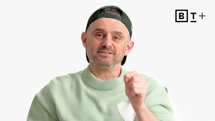 A man in a light green sweater and backward cap gestures with his hand against a plain white background. BT+ logo is visible in the top right corner.