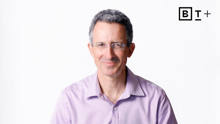 A man with short gray hair and glasses wearing a light purple shirt smiles at the camera; a black "BT+" logo appears in the top right corner.