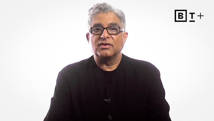 A man with gray hair and glasses wearing a black shirt speaks in front of a plain white background with a "BT+" logo in the corner.
