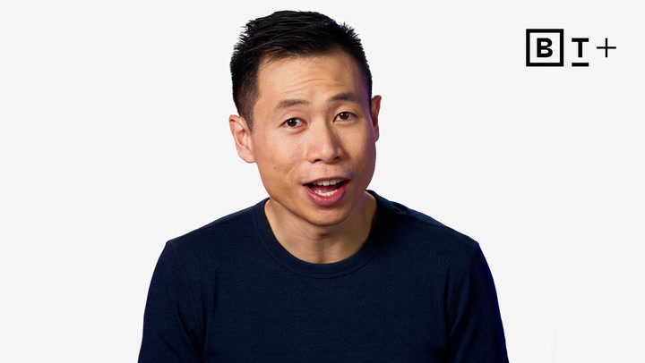 A person with short black hair and a dark shirt speaks in front of a white background with the B+ logo in the top right corner.