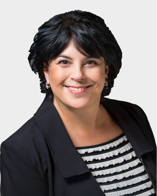 Woman with short dark hair wearing a black blazer and a black-and-white striped top, smiling at the camera against a plain white background.