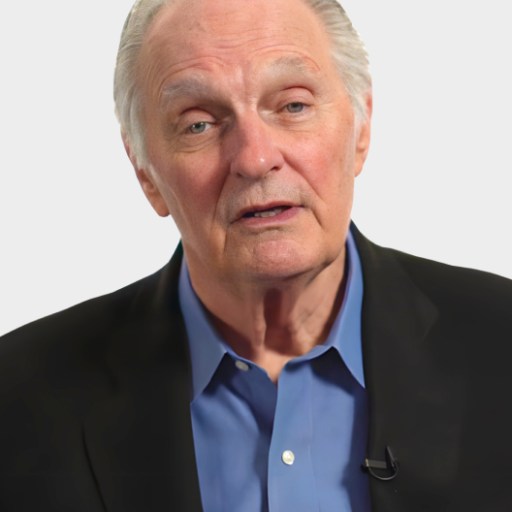 An older man with gray hair wearing a black suit jacket and blue shirt faces the camera with a neutral expression.