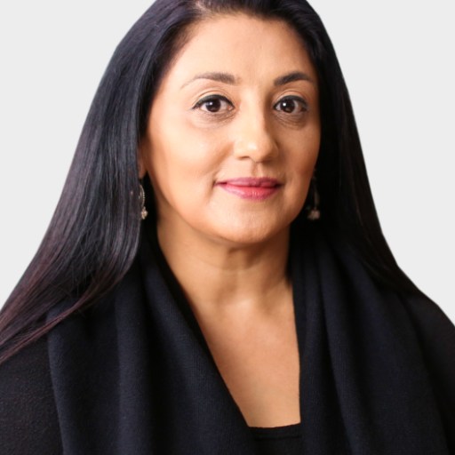 A woman with long dark hair and a neutral expression wears a black top and earrings, posing against a plain light background.