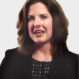 A woman with shoulder-length brown hair wearing a black blazer is speaking, with a neutral light gray background.