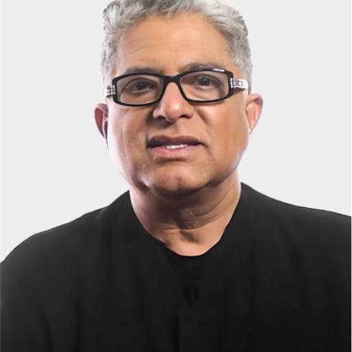 A middle-aged person with short gray hair and glasses, wearing a black shirt, is facing forward against a plain light background.