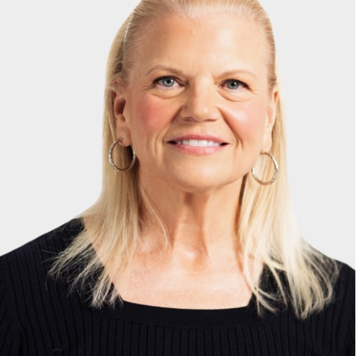 A woman with straight, shoulder-length blonde hair, wearing hoop earrings and a black ribbed top, smiles at the camera against a plain light background.