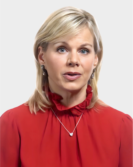 A woman with blonde hair wearing a red blouse, silver earrings, and a necklace is looking slightly upward against a plain light background.