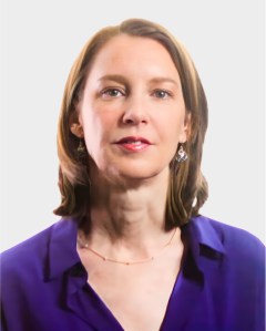 A woman with shoulder-length brown hair, wearing a purple blouse, drop earrings, and a delicate necklace, poses against a plain light background.