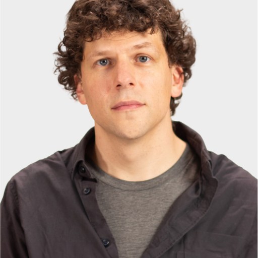 A man with curly brown hair wearing a dark button-up shirt over a gray t-shirt, looking directly at the camera against a plain light background.