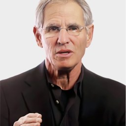 An older man with gray hair and glasses, wearing a black jacket and shirt, gestures with his right hand against a plain light background.