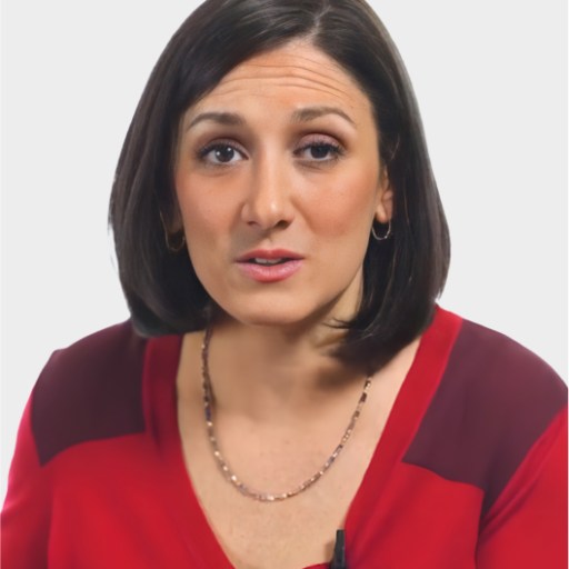 A woman with straight, shoulder-length dark hair wears a red blouse and a necklace, facing forward with a neutral expression against a plain white background.