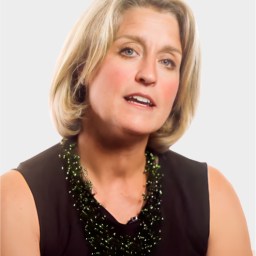 A woman with short blond hair, wearing a black sleeveless top and a dark beaded necklace, is looking slightly to the side against a plain light background.