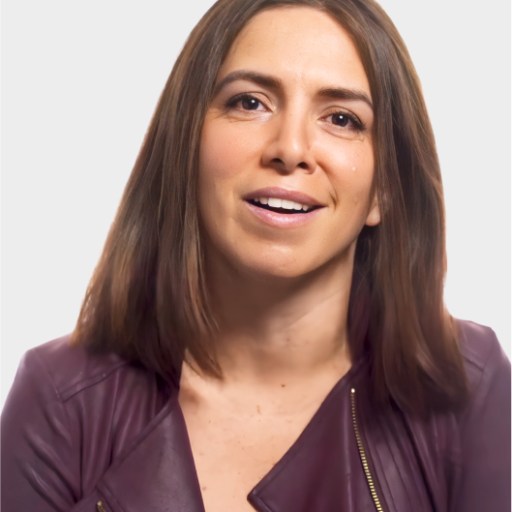 A woman with straight, shoulder-length brown hair wearing a maroon jacket sits against a plain light background, looking forward with a neutral expression.