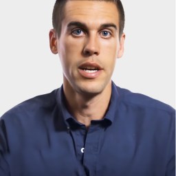 A man with short dark hair, wearing a navy blue button-up shirt, looks forward with a neutral expression against a plain white background.