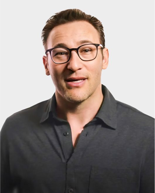 A man with short brown hair and glasses wearing a dark button-up shirt stands against a plain light background.