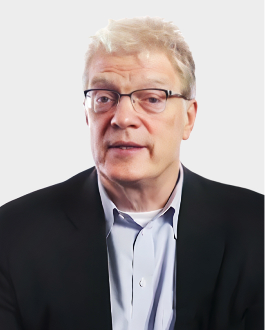 A middle-aged man with light hair and glasses, wearing a dark blazer and light blue shirt, poses against a plain white background.