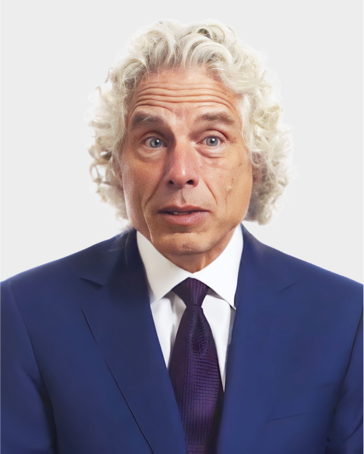 A man with curly gray hair wearing a blue suit, white shirt, and dark tie poses against a plain light background.
