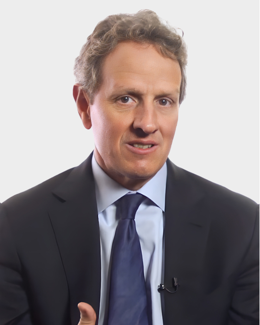 A man in a suit and tie is speaking, looking slightly to the side, with a neutral background.
