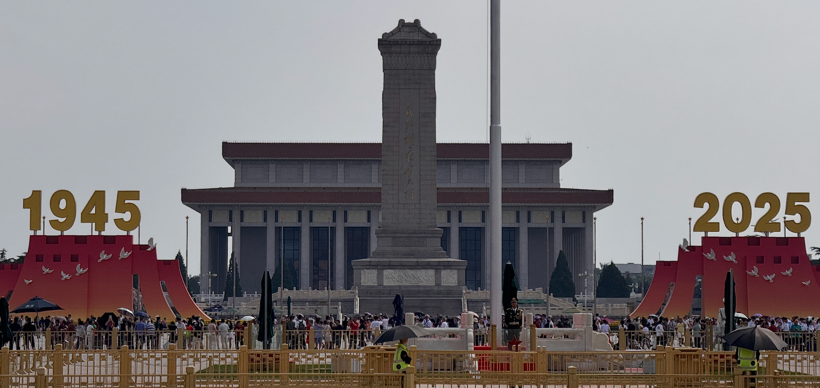 Crowds gather in front of the Monument to the People's Heroes and Mao Zedong Mausoleum in Tiananmen Square, China, with large "1945" and "2025" signs displayed on either side.
